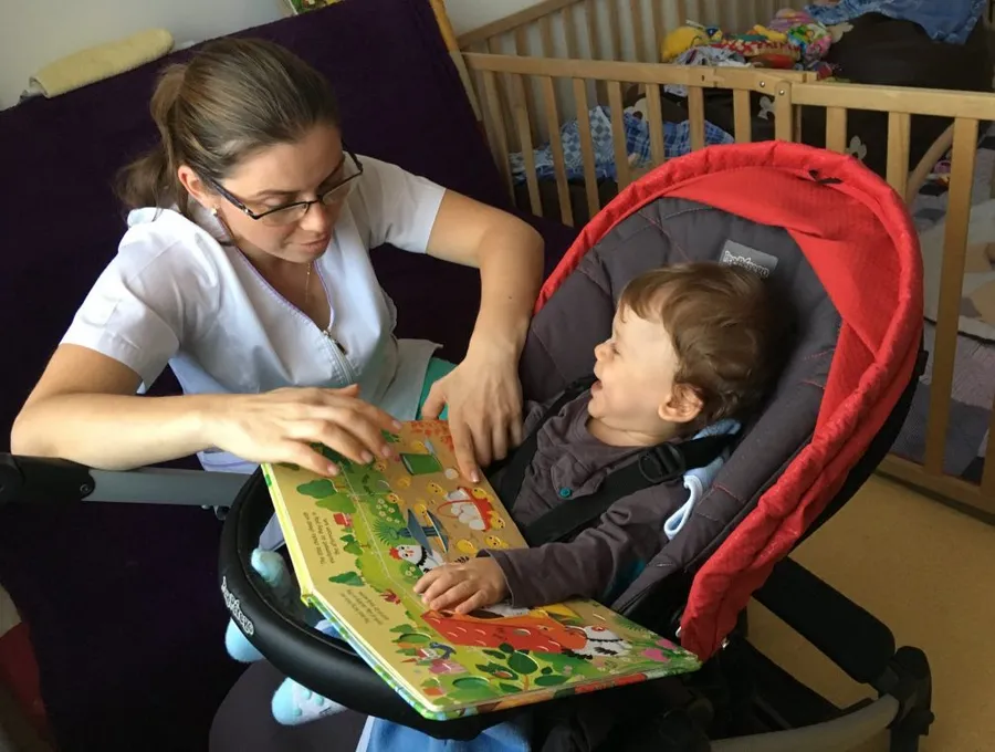A child and a caregiver reading together at the hospice